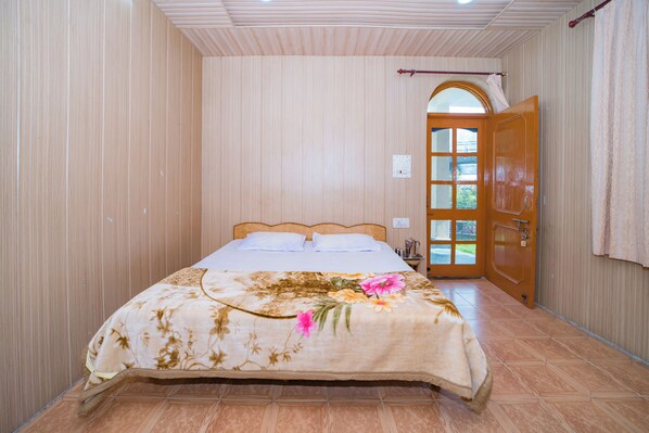 A bedroom with a bed, a wooden door, and a window. - Forest Rest House Barot (Barot)