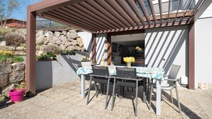 Une terrasse extérieure avec une table et des chaises, une pergola et un mur en pierre.