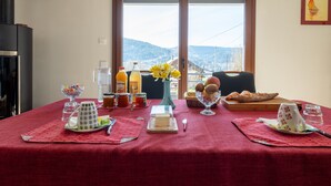 Une table à manger recouverte d’une nappe rouge, avec différents plats et un vase rempli de fleurs jaunes.