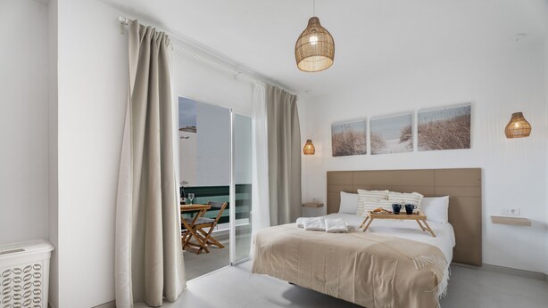 Un dormitorio con cama, una mesa de comedor y vistas a través de un ventanal corredero.