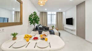 Una sala moderna con comedor, televisor de pantalla plana y un espejo grande.