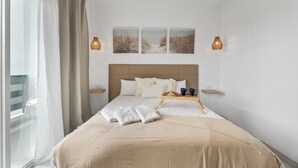 Una habitación de hotel con una cama, una ventana con cortinas, una mesita de noche con una bandeja y decoración en la pared.