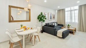 Una sala de estar moderna con comedor, un sofá gris, una mesa de centro y un espejo grande.