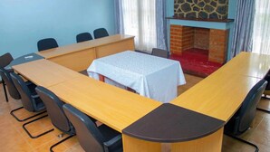 A conference room with a long table, chairs, a small table with a white tablecloth, and a stone fireplace.