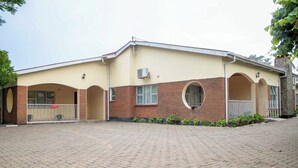 A two-story building with a brick facade, a circular window on the second floor, and a paved driveway.