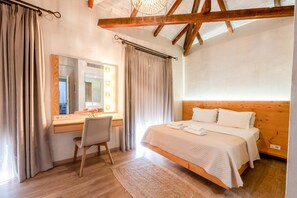 Ein Schlafzimmer mit einem hölzernen Bett, einem Schreibtisch mit Stuhl, einem Spiegel und einem Fenster mit Vorhängen.
