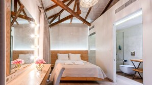 Un dormitorio moderno con techo de madera, una cama con ropa blanca, un escritorio de madera y un espejo.