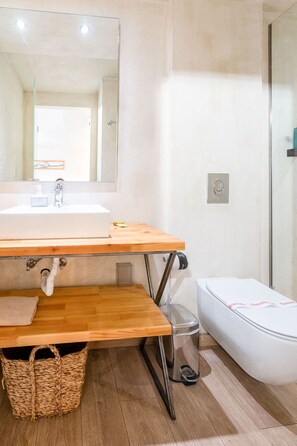 A bathroom with a wooden vanity, a white sink, a mirror, a shower, and a toilet. - Panellinion Beachfront Getaway Balcony w Seaview (Kalamata)