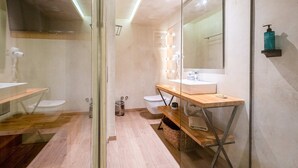 Un baño moderno con cabina de ducha de vidrio, tocador con espejo y lavamanos.
