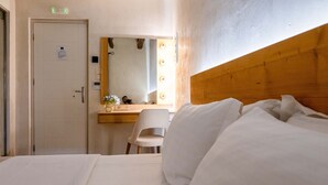 Habitación de hotel con cama, cabecero de madera, escritorio con silla y espejo con iluminación.