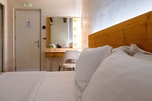 Habitación de hotel con cama, cabecero de madera, escritorio con silla y espejo con iluminación.