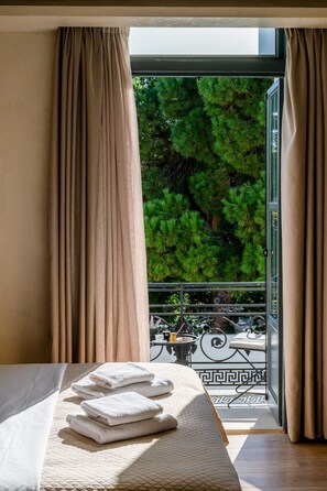 Ein Hotelzimmer mit Bett, einem Balkon mit Blick auf Bäume und einem Tisch mit einer Dekoration.