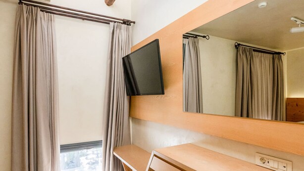 A room with a wooden desk, a chair, a TV mounted on the wall, and a large mirror. - Panellinion Beachfront Gem Comfy Cozy Triple (Kalamata)