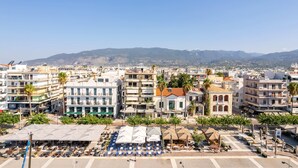 A coastal cityscape with multi-story buildings, a clear sky, and distant mountains. - Panellinion Beachfront Gem Comfy Cozy Triple (Kalamata)