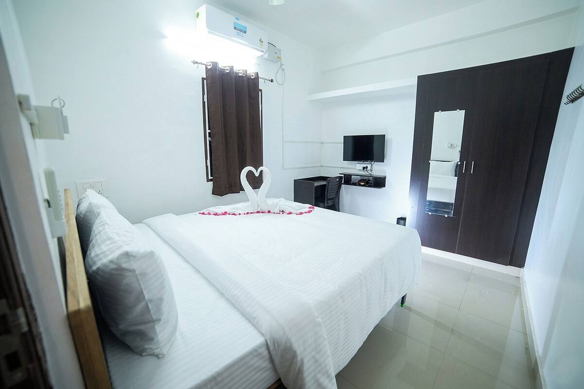 Una habitación de hotel con cama, televisión, escritorio y armario.