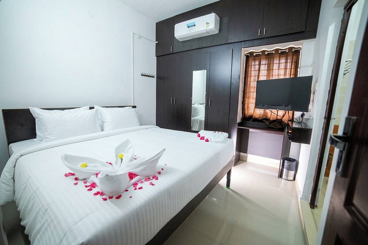 Una habitación de hotel con cama, televisión, armario y aire acondicionado.