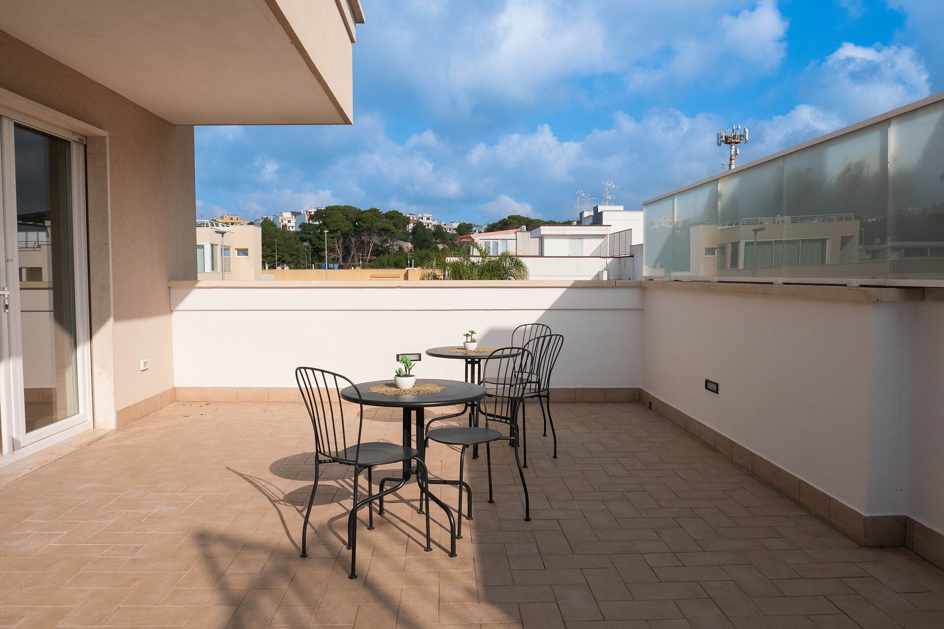 Una terrazza sul tetto con tavolo e sedie, una pianta in vaso e vista sulla città.