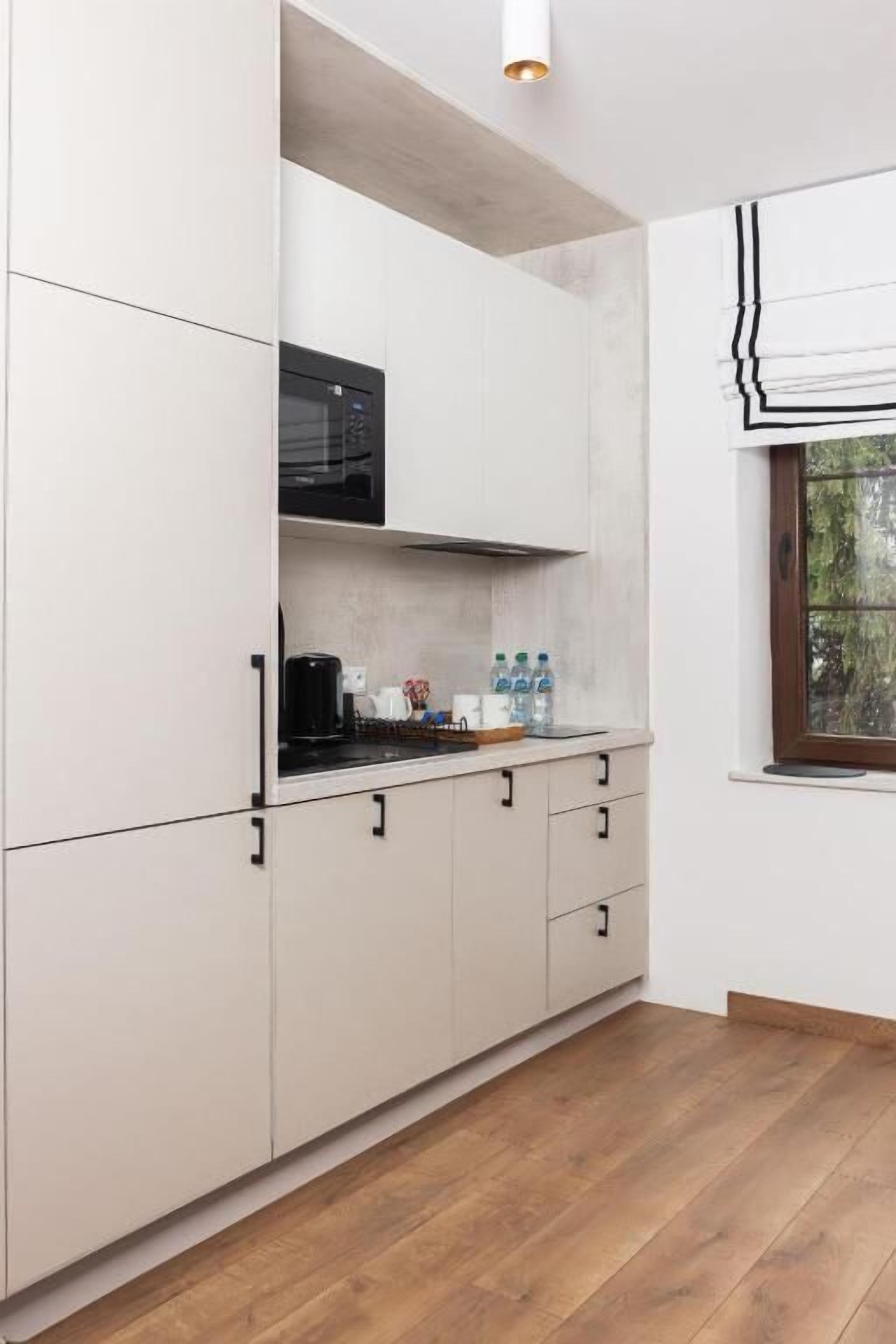 Una cocina moderna con armarios blancos, un microondas y una ventana con vista a la vegetación.