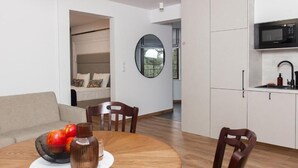 A modern living space with a dining area, kitchen, and a view through a window. - Lipowa32 Apartamenty (Hrubieszów)