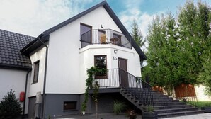 A two-story house with a balcony, a staircase, and a number '32B' on the front. - Lipowa32 Apartamenty (Hrubieszów)