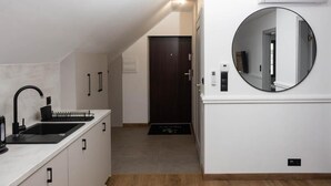 A modern kitchen with a black sink, white cabinets, and a round mirror on the wall. - Lipowa32 Apartamenty (Hrubiesz ów)
