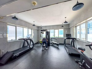 A gym with treadmills, a weight machine, and a person using a bike. - Free Housekeeping Visits During Your Stay - Stayshort - Chic 1BR in Dubai Marina Sleeps 2 (Dubai)