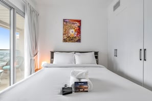 A hotel room with a bed, a window with curtains, a painting on the wall, and a 'Thank You' card on the bed. - Free Housekeeping Visits During Your Stay - Stayshort - Chic 1BR in Dubai Marina Sleeps 2 (Dubai)