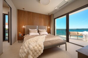 A bedroom with a large bed, a view of the sea, and a balcony with a sofa. - Luxury Beachfront Villa Malia Trogir with Pool (SegetDonji)