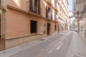 A narrow street with buildings on either side, a blue AT sign, and a visible door. - Suite Plaza Nueva. Comfort in the center of Granada (Granada)