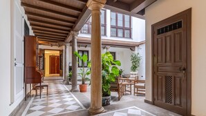 Un patio amplio con piso de diseño escocés, mobiliario de madera y plantas en macetas.