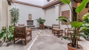 Un espacio interior amplio con techo alto, chimenea y varias plantas en macetas.