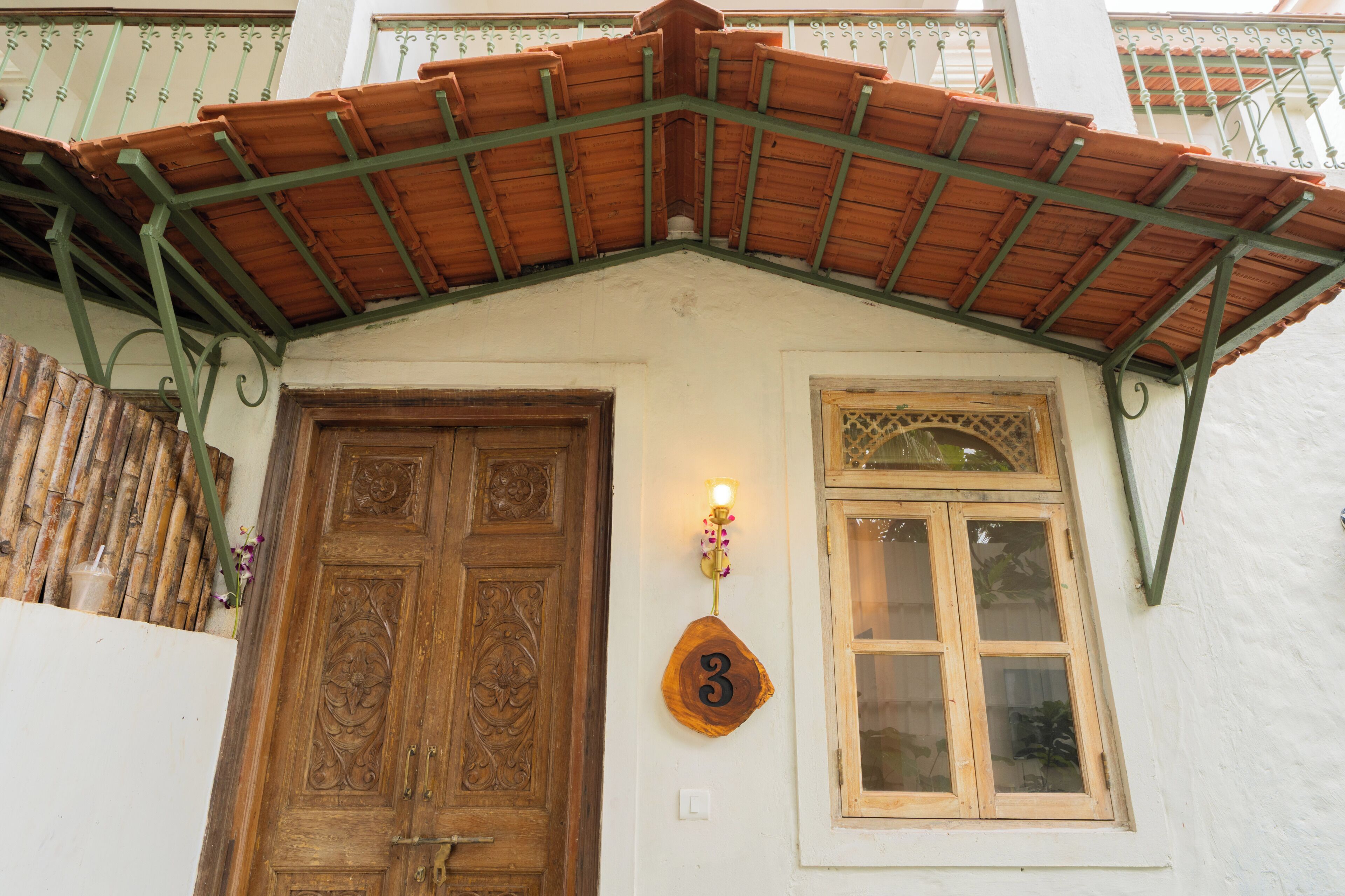 Un edificio con puerta de madera, ventana con placa de número y tejado de tejas.