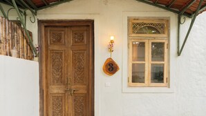 Una puerta doble de madera con intrincados grabados, una pequeña ventana con marco de madera y un letrero con el número 3 en la pared.