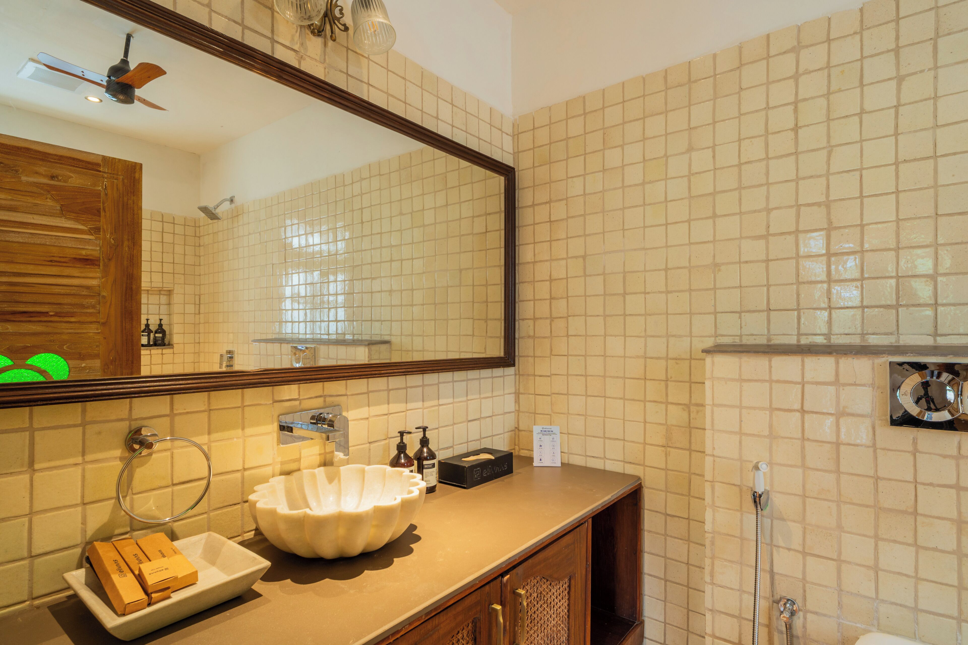 A bathroom with a large mirror, a sink with a bowl, a shower, and a wooden cabinet.