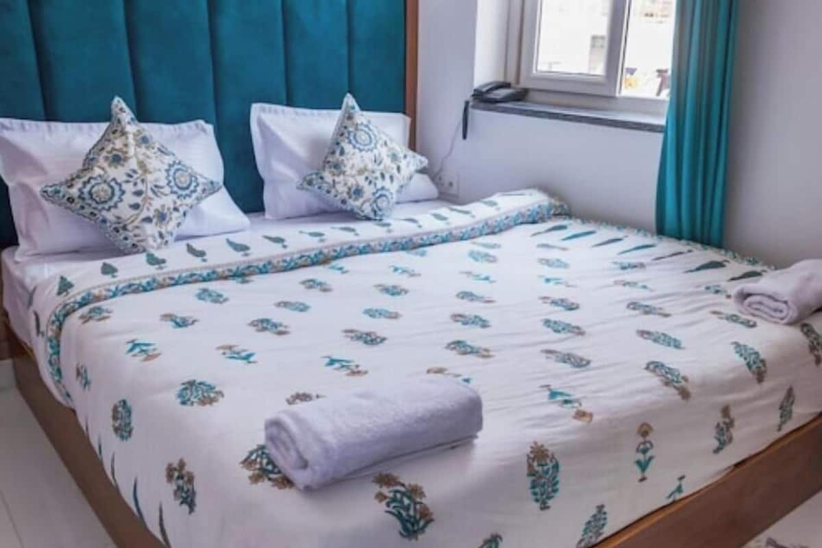 Ein Bett mit einem gemusterten Überwurf, zwei Kissen und einem gefalteten Handtuch.
