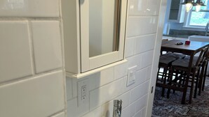Un baño con lavamanos blanco, un espejo y un mueble de madera.