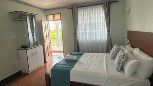 Un dormitorio con cama, ventilador de techo, armario y ventana con cortinas.