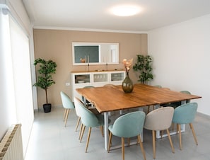 A dining area with a wooden table, six chairs, a vase with flowers, and a cabinet with glass doors. - Casa 'La Marisol Ribeira' with Sea Views, Private Terrace and Wi-Fi (A Coruña)