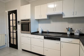 A modern kitchen with white cabinets, a black countertop, and stainless steel appliances including an oven and dishwasher. - Casa 'La Marisol Ribeira' with Sea Views, Private Terrace and Wi-Fi (A Coruña)