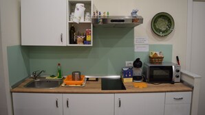 Una cocina con un lavamanos, un microondas, un tostador y varios utensilios de cocina sobre la encimera.