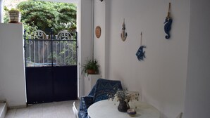 Una habitación con una mesa redonda, una silla, una planta en maceta y vistas a una puerta y follaje exterior.