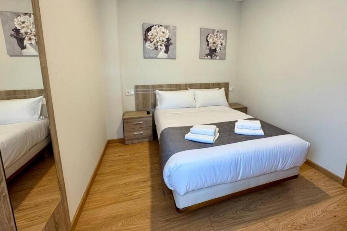 A bedroom with a bed, bedside tables, and artwork on the wall.