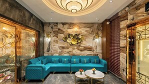Een modern interieur met een smaragdgroene bank, marmeren wanden en een kroonluchter.