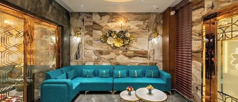 A modern interior with a teal sofa, marble walls, and a chandelier.