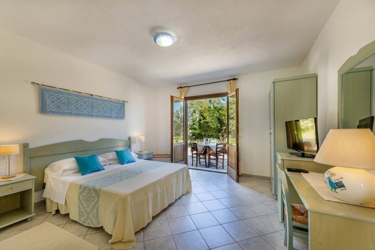 Une chambre à coucher avec un lit, un bureau, une télévision et une vue sur l’extérieur.
