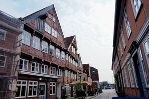 A narrow street lined with traditional brick buildings, some with shops and signage. - Elbquartier AltesLand – Apartment 1 (Hollern-Twielenfleth)