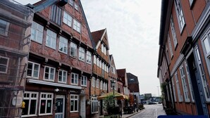 Eine schmale Straße gesäumt von traditionellen Backsteingebäuden, einige davon mit Geschäften und Schilder.