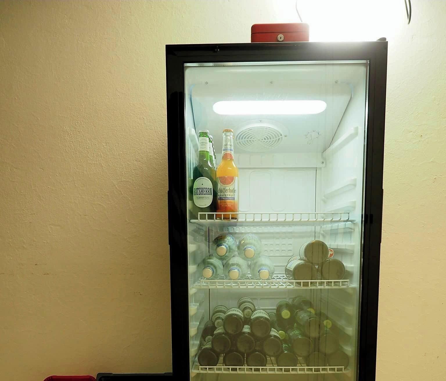 A mini-fridge with a red top, containing bottles of water and juice, and a bottle of wine.