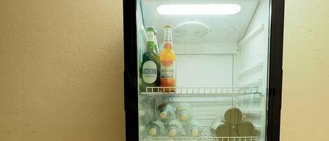 A mini-fridge with a red top, containing bottles of water and juice, and a bottle of wine.