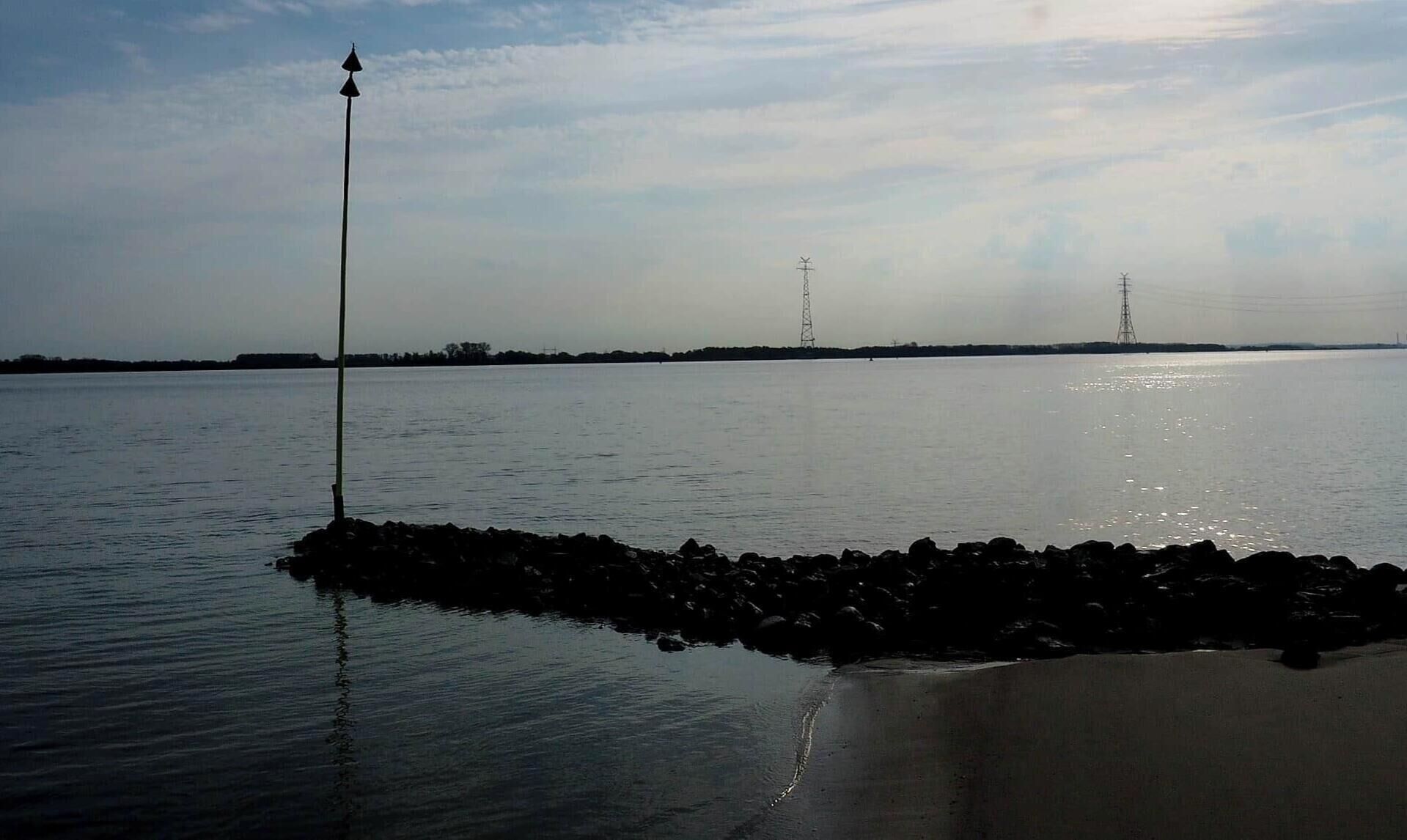 A calm body of water with a pier extending into it, surrounded by rocks.